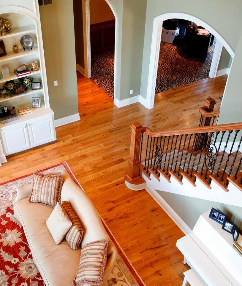 Spacious interior with hardwood floors, staircase, built-in shelving, and a patterned rug.