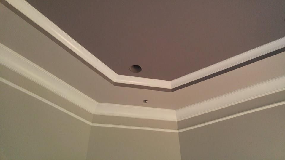 Corner of a room with a gray ceiling, white trim, and light gray walls.