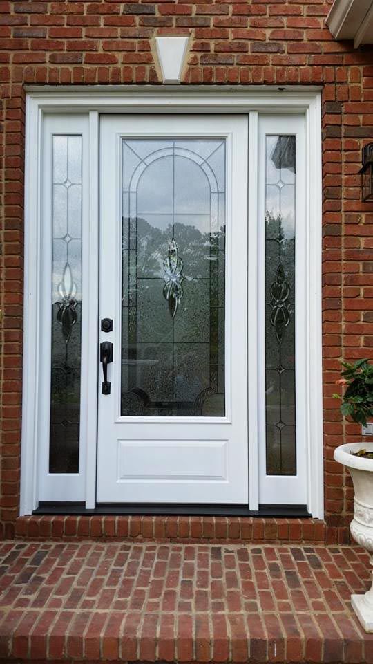 Front door with decorative glass against a dark brick wall.