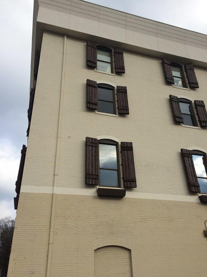 Beige building with brown shutters and windows.