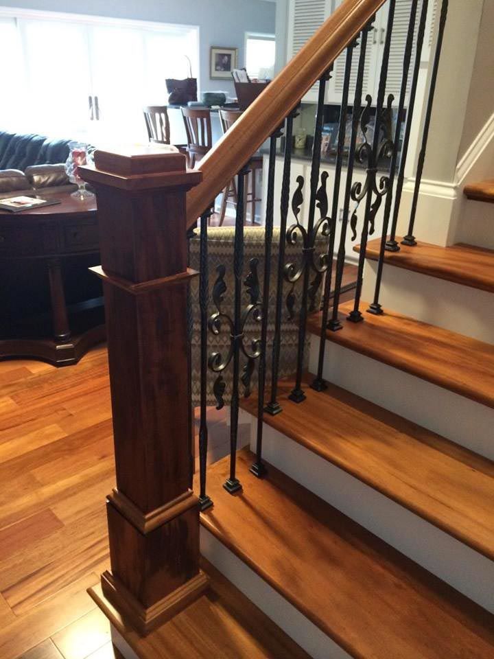 Wooden staircase with dark wood railing and black iron balusters.