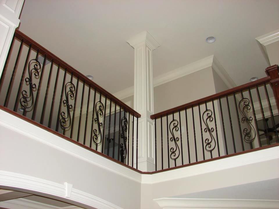 Interior view of a second-story balcony with decorative ironwork railings and a central white pillar.