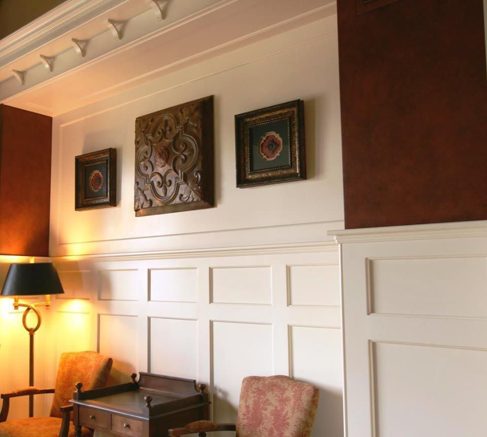 White paneled walls with framed art, and dark accent wall.