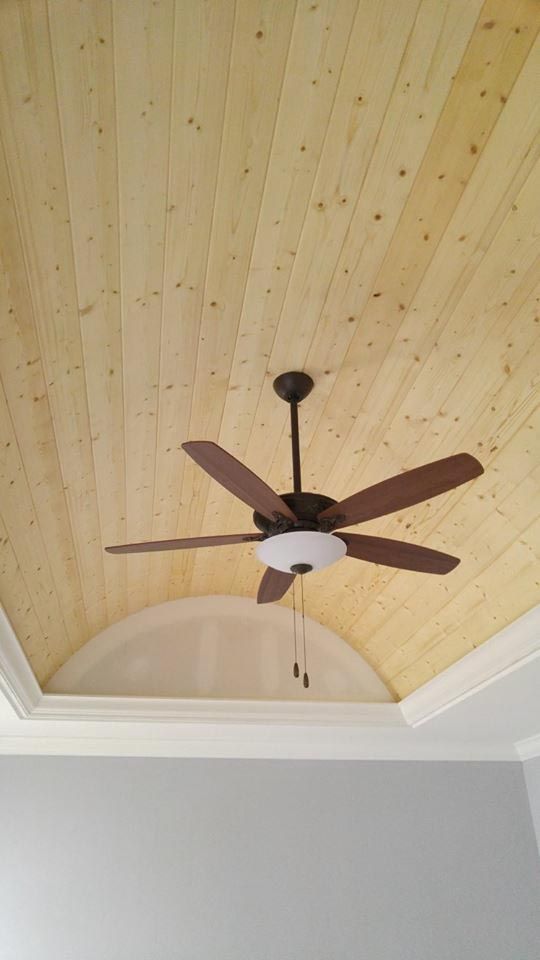 Wooden plank ceiling with a brown ceiling fan and white trim.