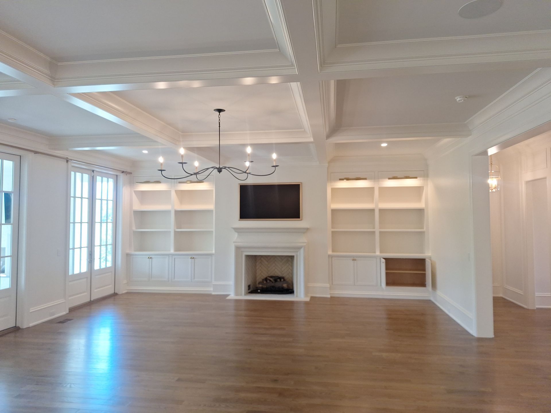 White fireplace mantel with a wide, classic surround and herringbone tile firebox, flanked by built-in bookshelves