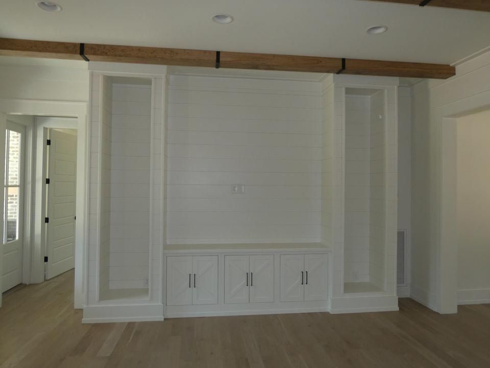 Built-in white cabinet and shelving unit on a wall, with wooden beams above.