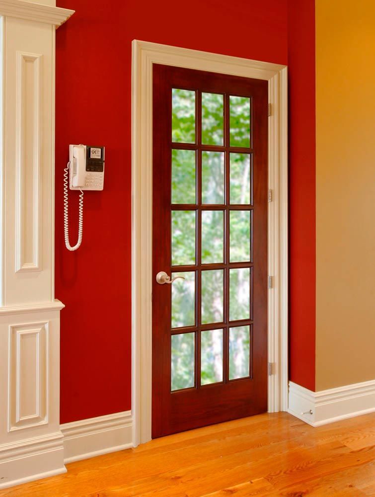 Door with glass panes, framed in white, set in a red wall. Phone mounted beside the door.