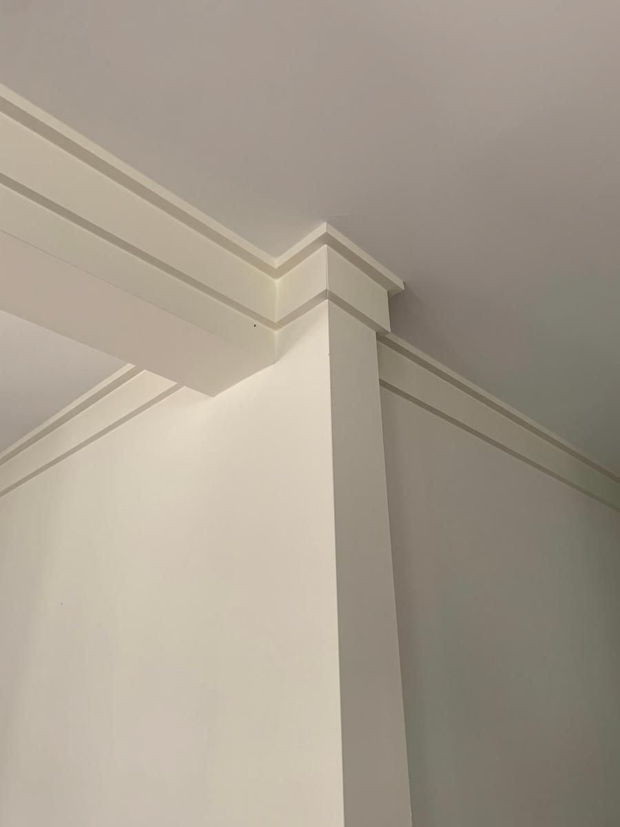 White interior corner with crown molding and flat, white walls.