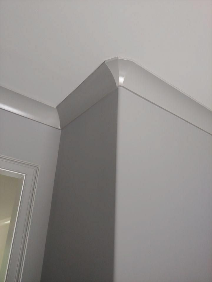 Gray crown molding at a corner of a room, painted white against a gray wall and ceiling.