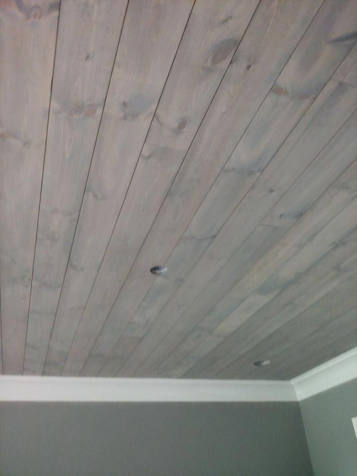 Gray wooden plank ceiling with recessed lighting and white molding.