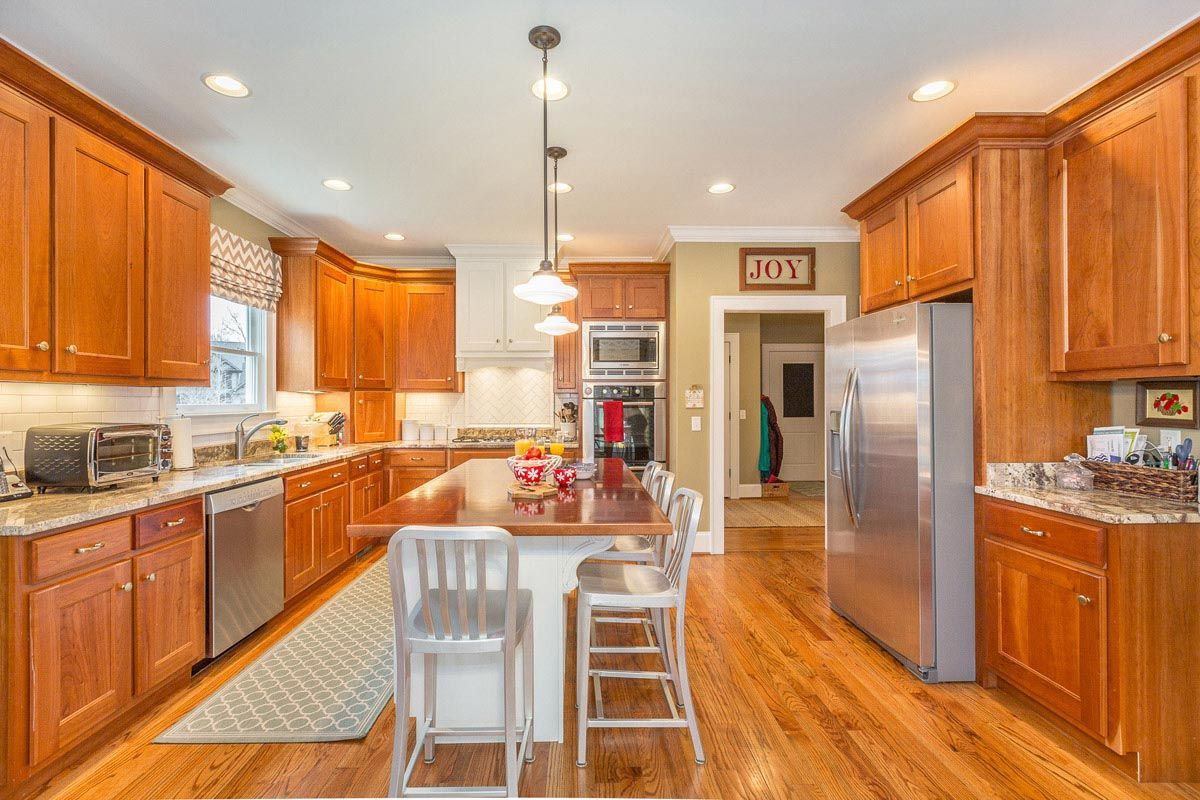 Kitchen with wooden cabinets, stainless steel appliances, and an island with bar stools.