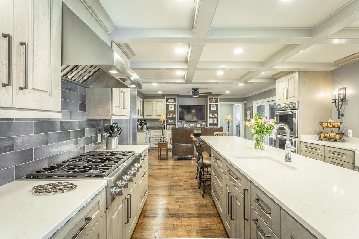Spacious kitchen with gray cabinets, white countertops, and stainless steel appliances; looking into the living room.