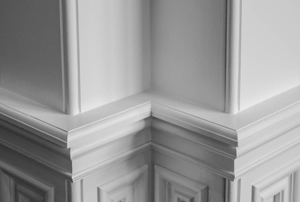 Corner of white paneled walls with decorative trim.