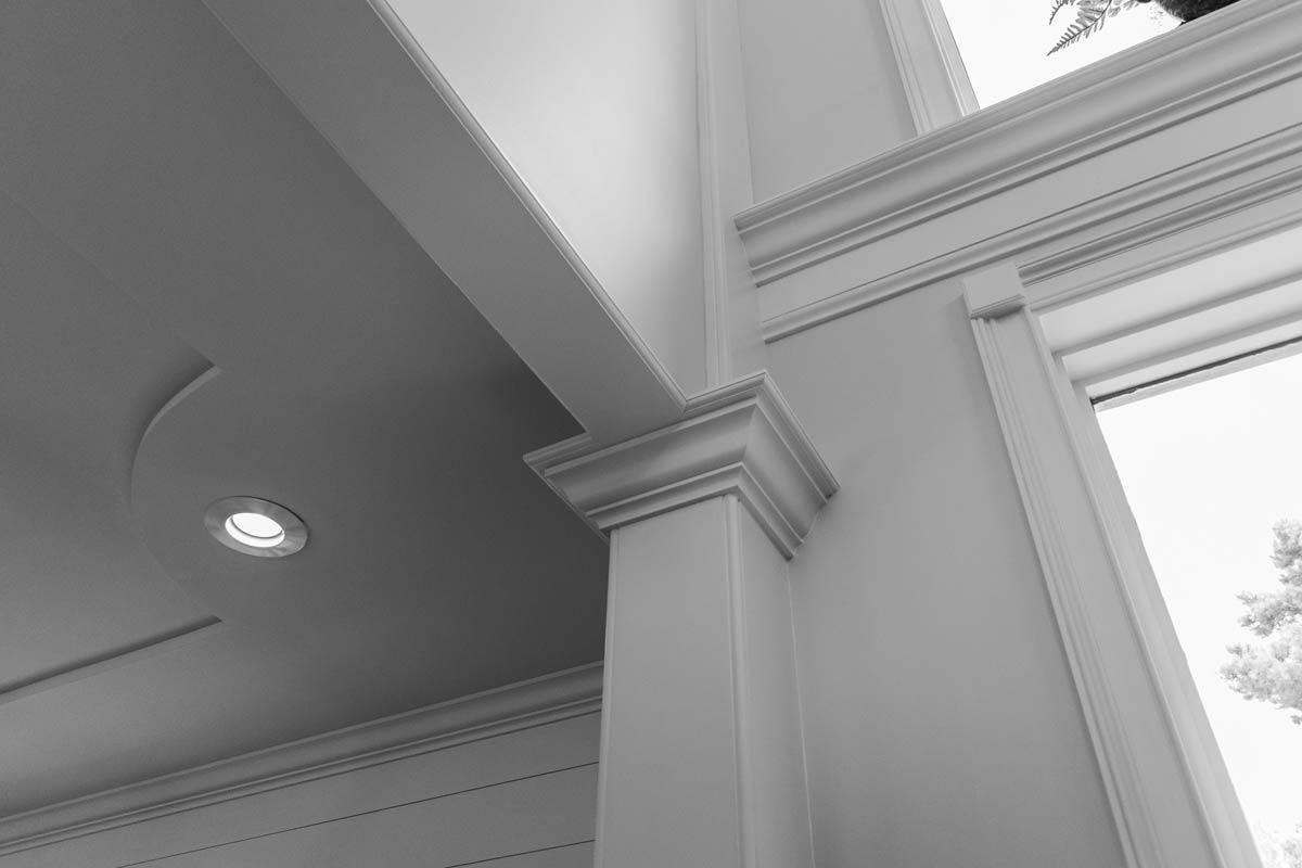 Interior architectural details: white column with crown molding, ceiling, and window frame.