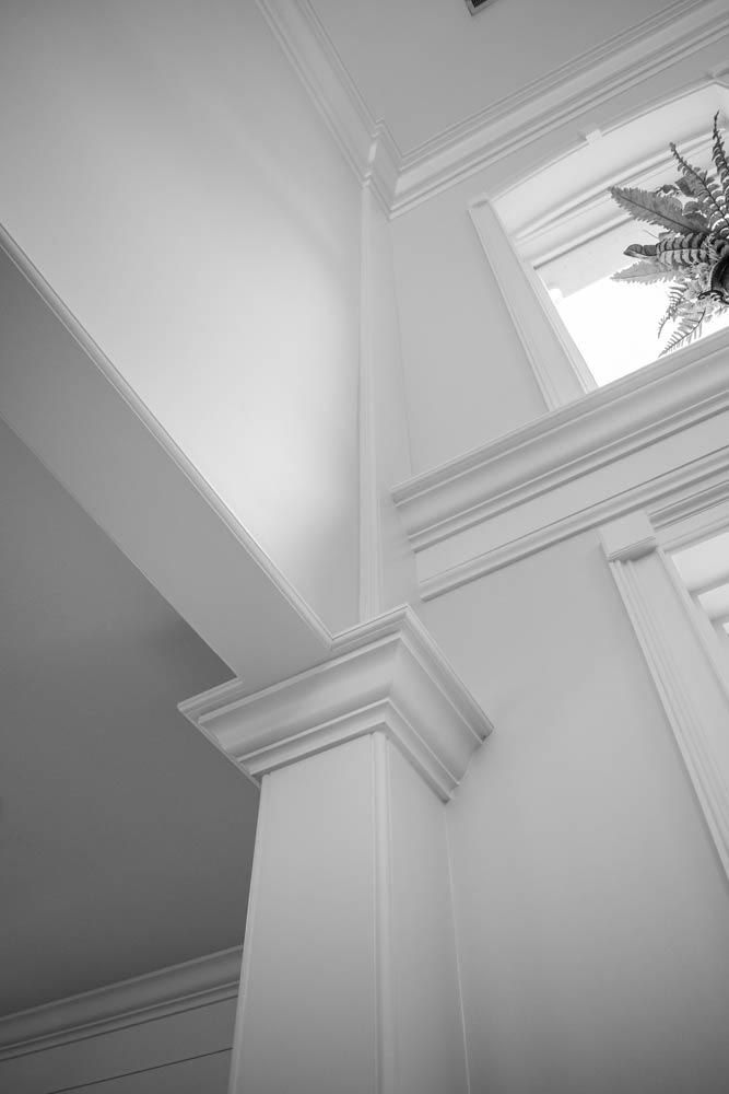 White interior corner with decorative molding and a window.