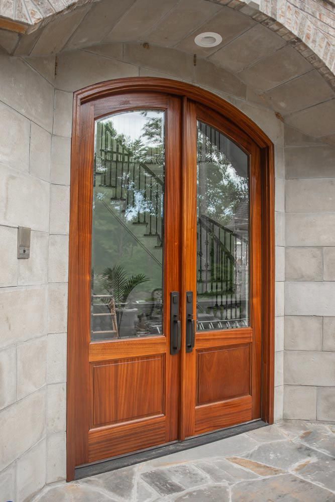 Side view of a stone entryway with double wood doors with large glass panes.