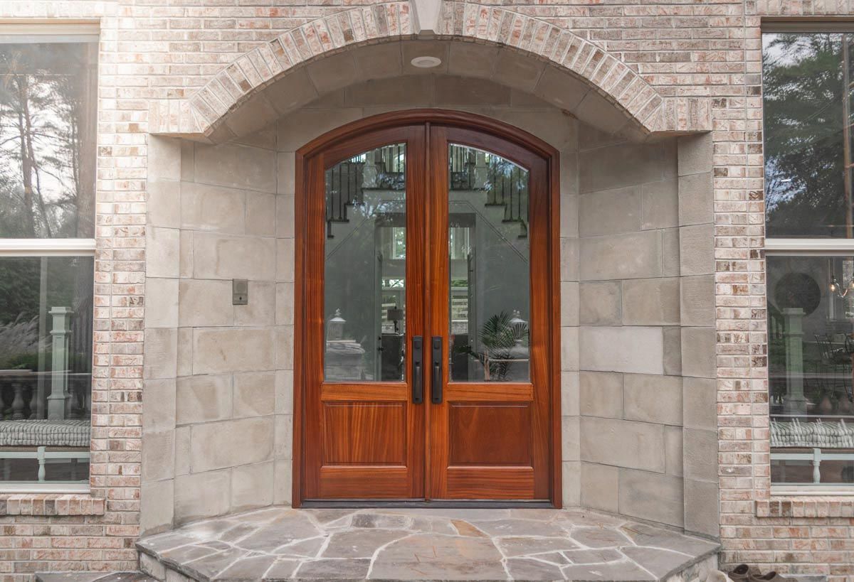 Stone entryway with brown double doors that have large glass pannels.