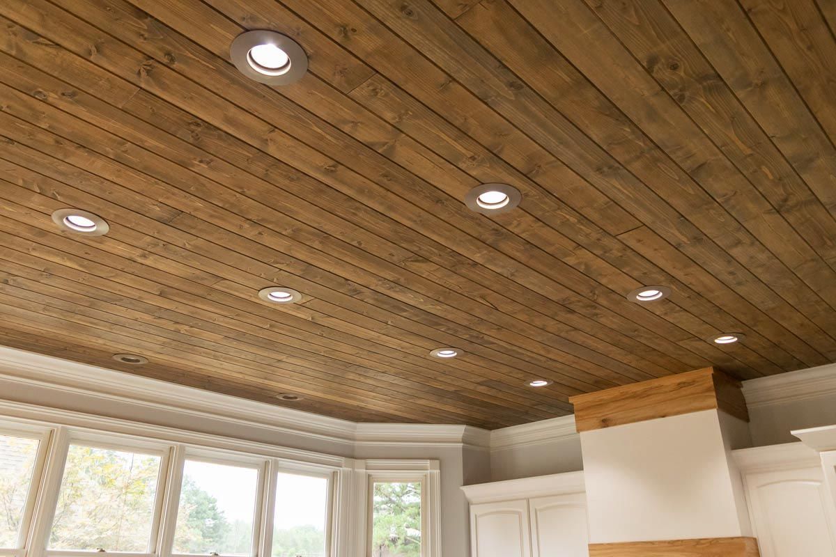 Wooden plank ceiling with recessed lights in a kitchen.