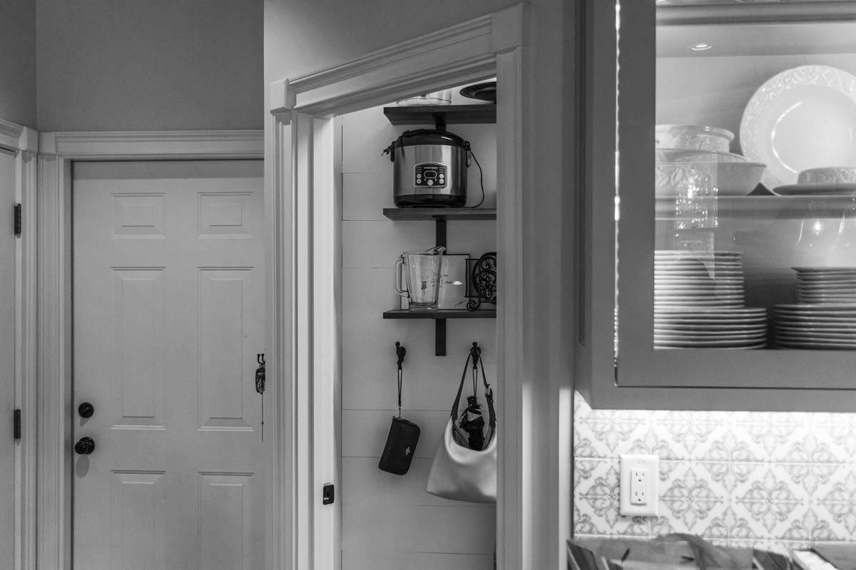 A black and white kitchen doorway view of a door, pantry, and dish cabinet.