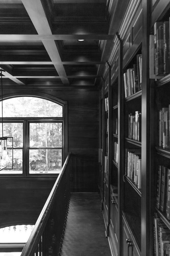 A library with built-in bookshelves, an arched window, and a coffered ceiling.