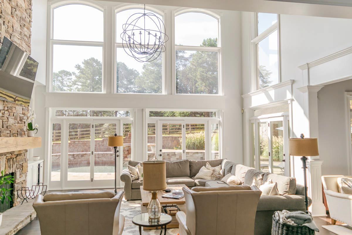 Spacious living room with large windows, a stone fireplace, and a neutral-toned sectional sofa.