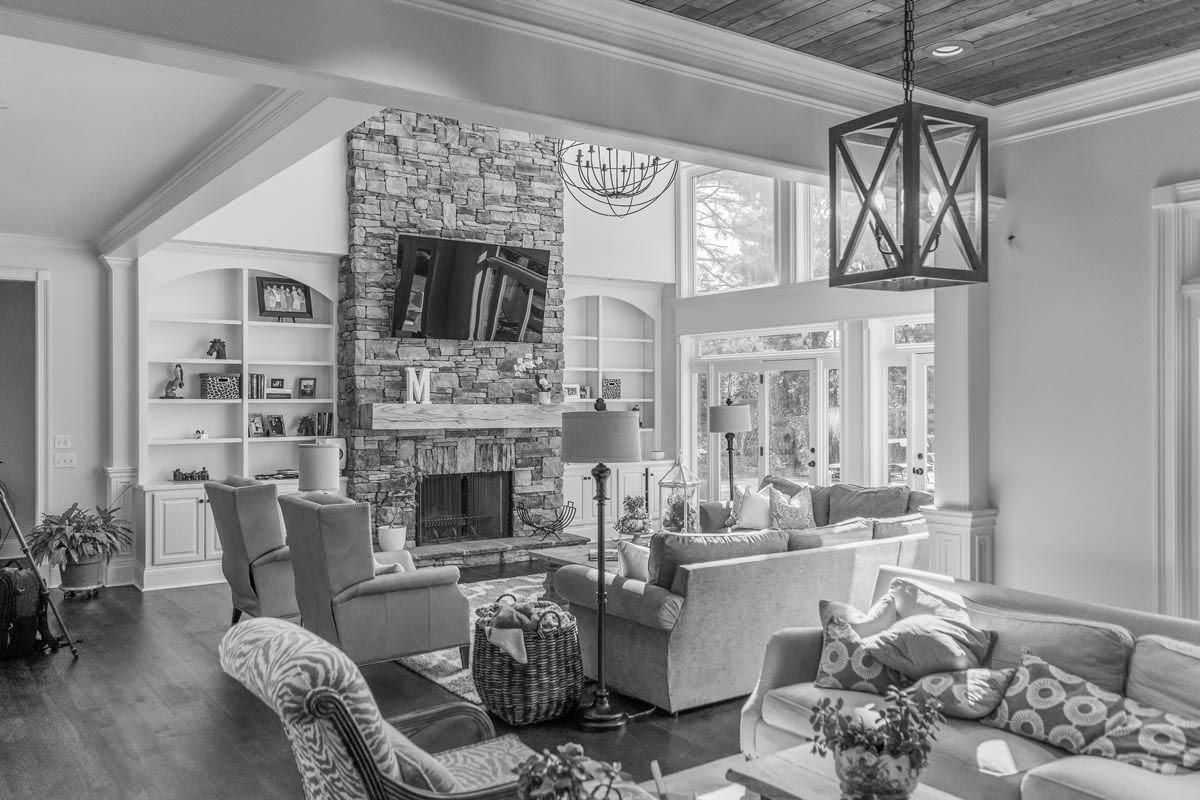 Living room with stone fireplace, built-in shelves, large windows, and contemporary furniture.