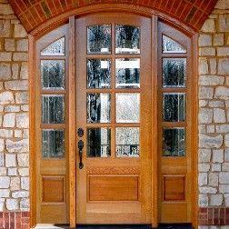 Wooden front door with glass panes and sidelights, set in a brick frame.