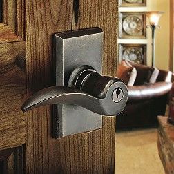 Bronze door handle with keyhole on a wooden door, partially open.