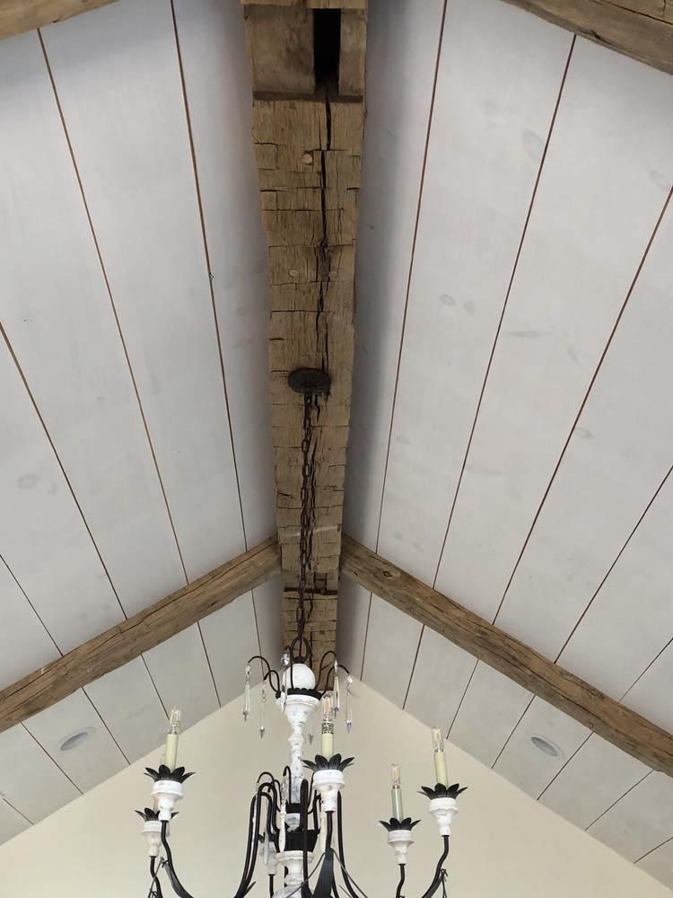 Whitewashed vaulted ceiling with exposed wooden beams, chandelier hanging below.