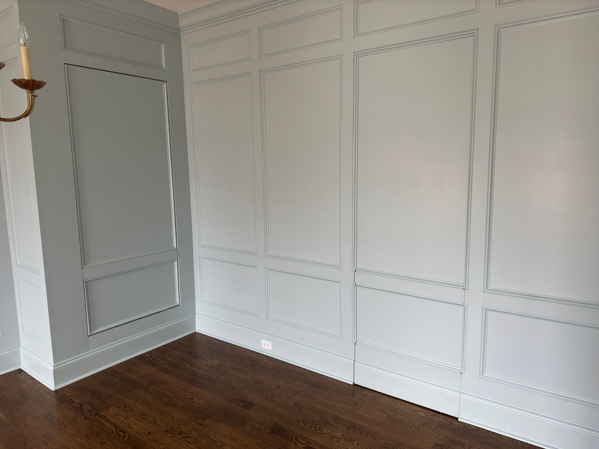 Light blue paneled walls with crown molding above dark wood flooring.