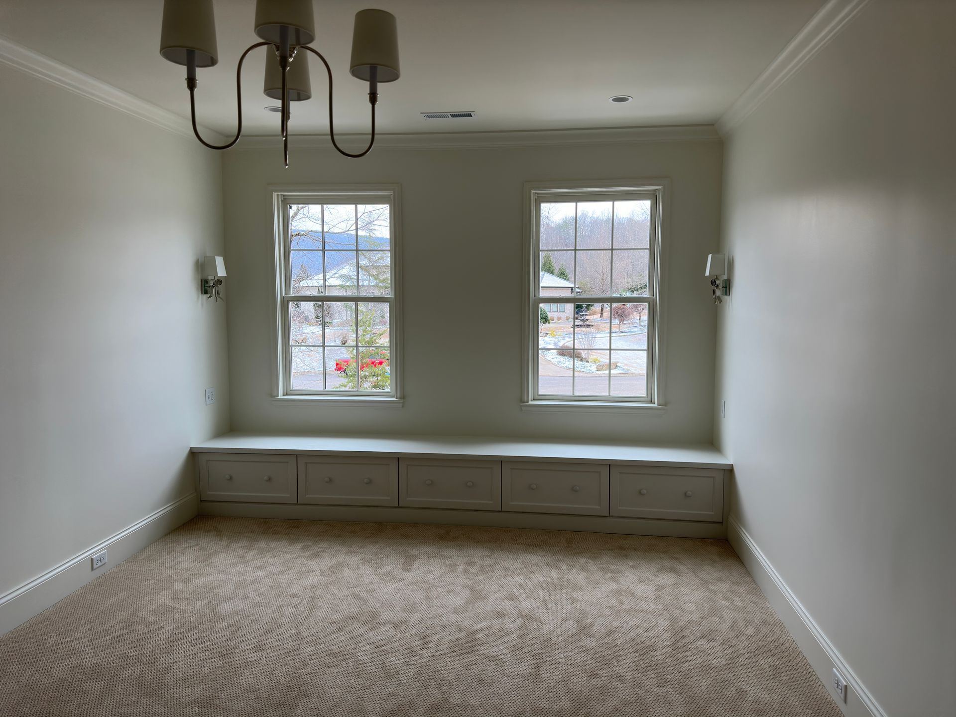 Empty room with two windows and a built-in bench, beige carpet, and white walls.