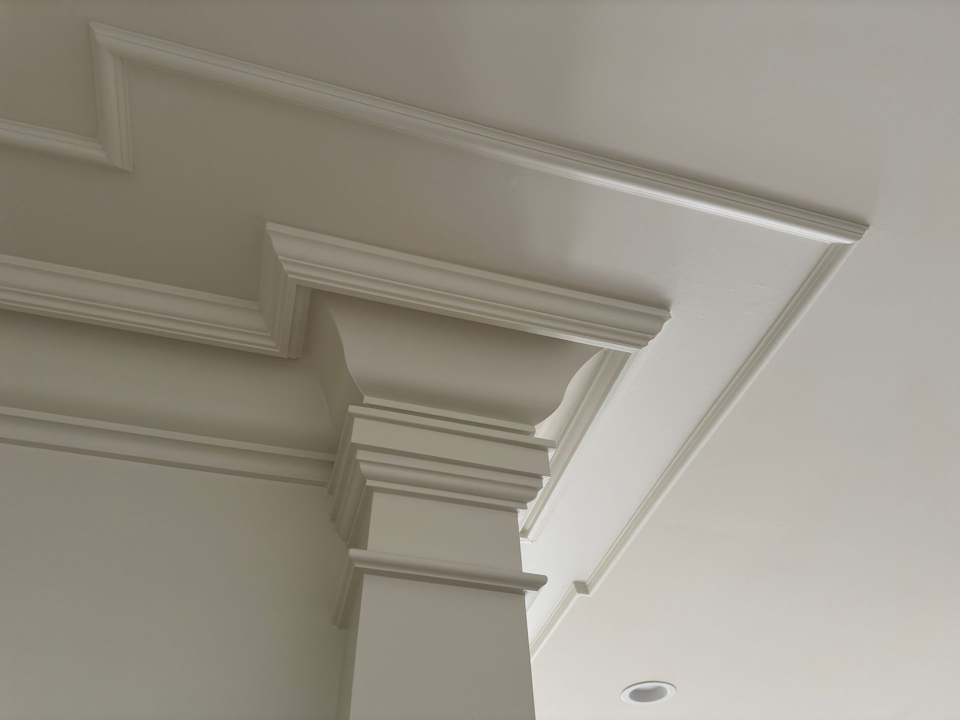 White painted pillar with ornate molding at ceiling corner.