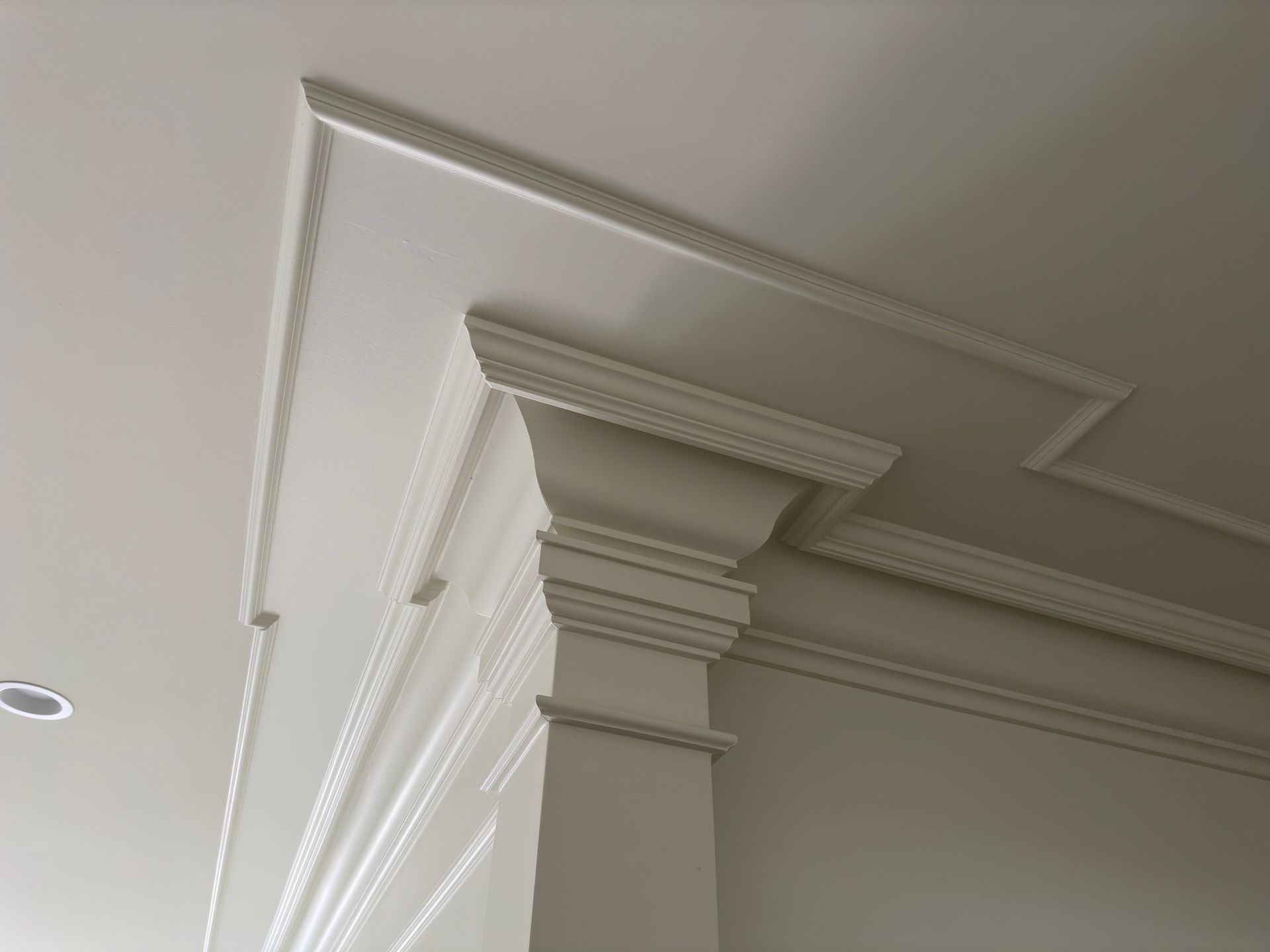 White decorative molding on a ceiling and wall corner, with layered, ornate details.