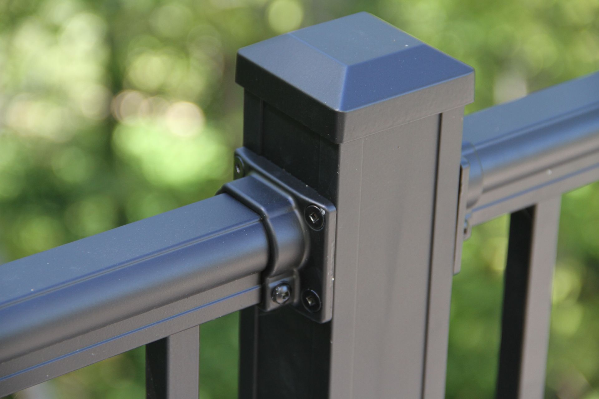 Black deck railing and post with a connected horizontal rail, outdoors.