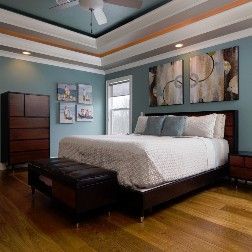 Bedroom with a blue wall, brown furniture, and abstract art above a bed.