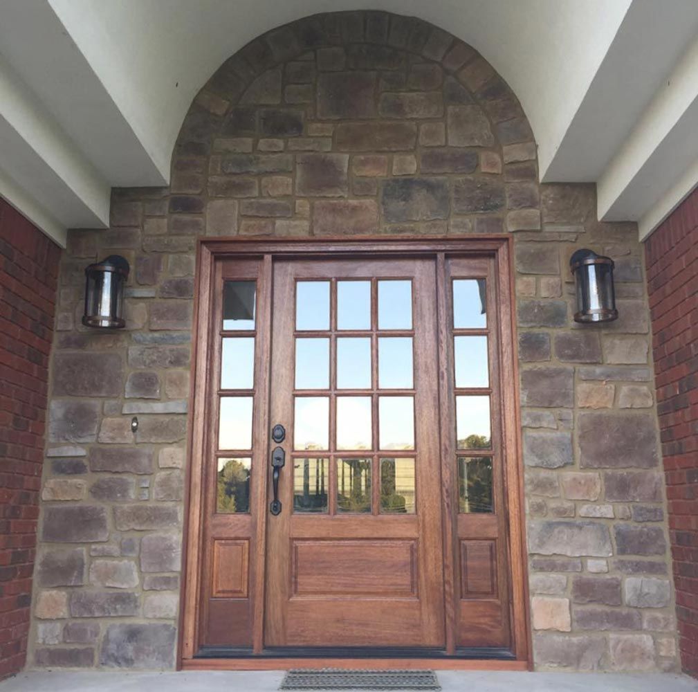 Mahogany wood door surrounded by brick at the front entrance of a home.