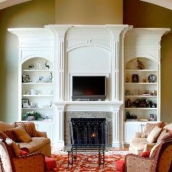 White built-in entertainment center with fireplace, TV, and arched bookshelves in a living room.