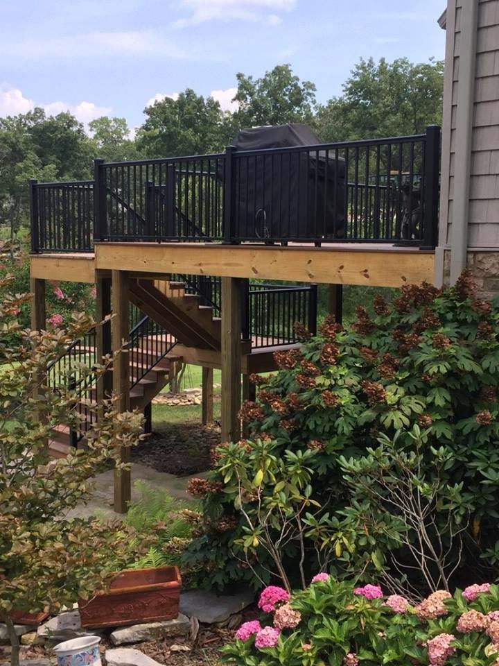 Back porch with wood decking, black iron rails, and a grill.