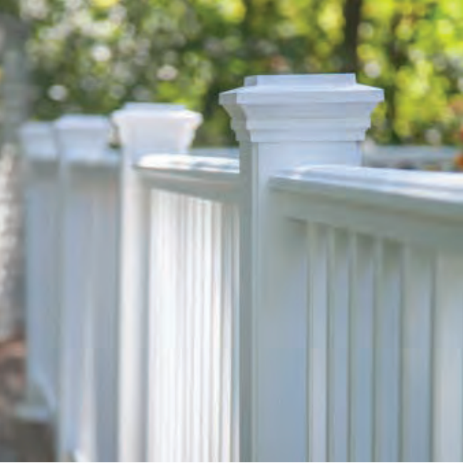 White picket fence with detailed posts, against a blurred green backdrop.