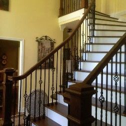 Wooden staircase with wrought iron balusters; brown railing and white steps.