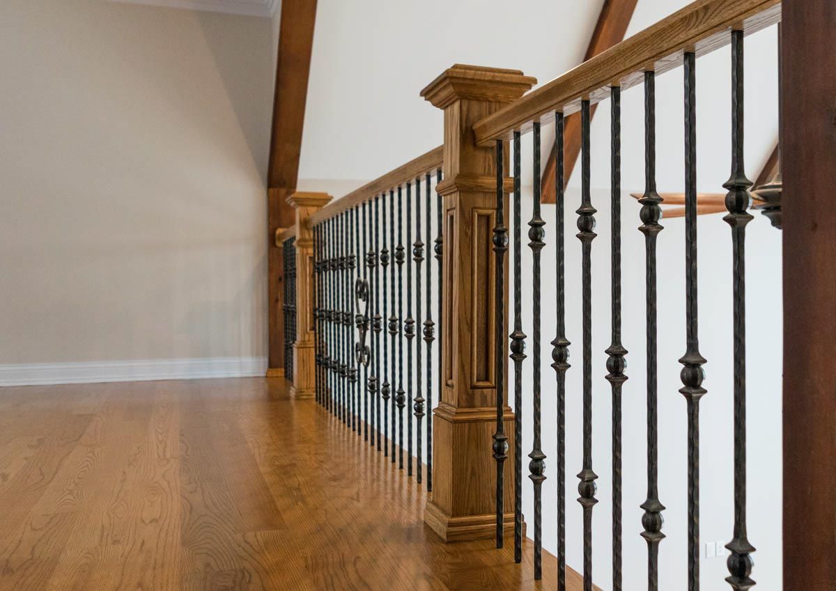 Wooden staircase with dark metal railings, brown wooden floor, and off-white walls.