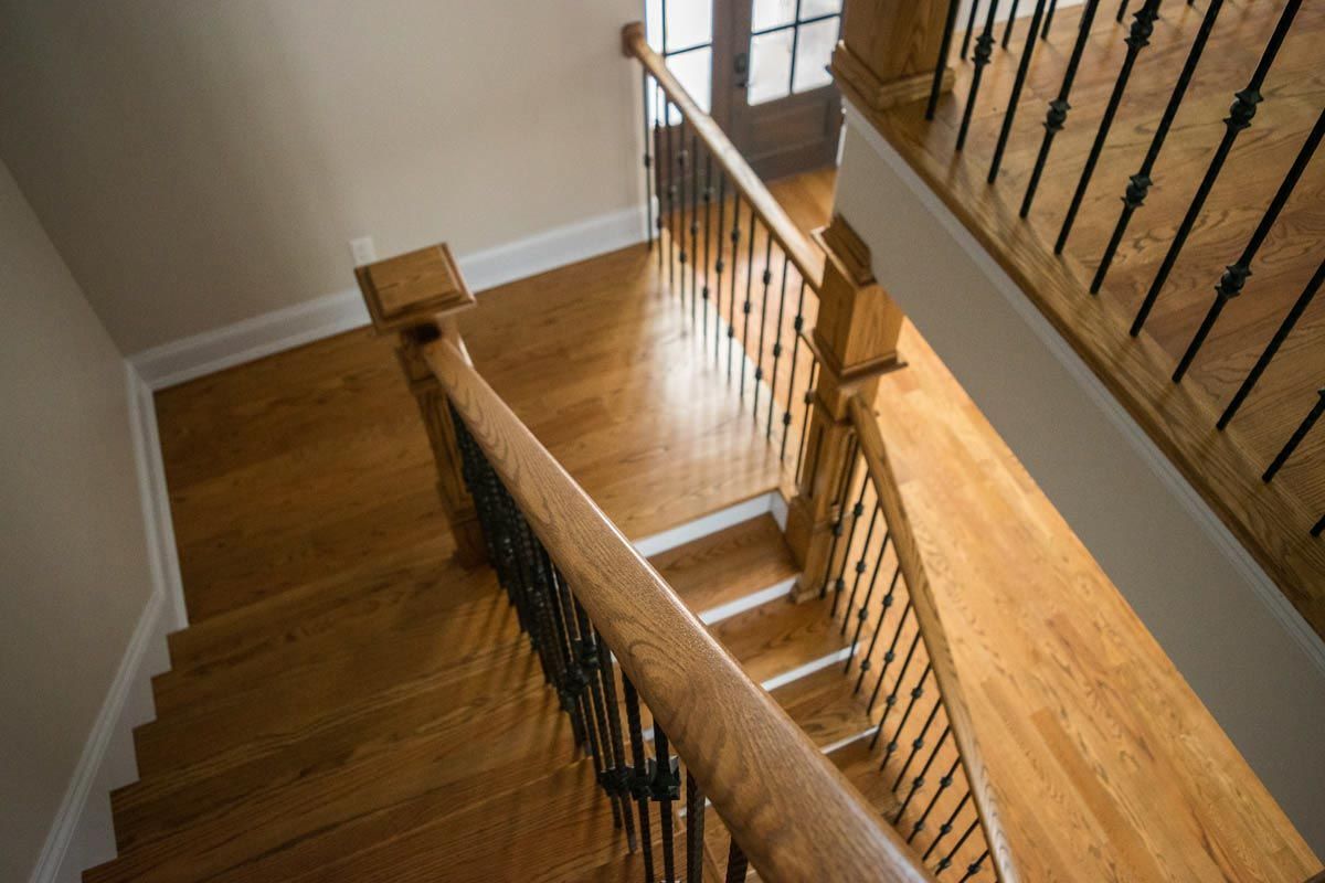 Wooden staircase with dark metal railings, leading to a doorway. Bright, hardwood floors.