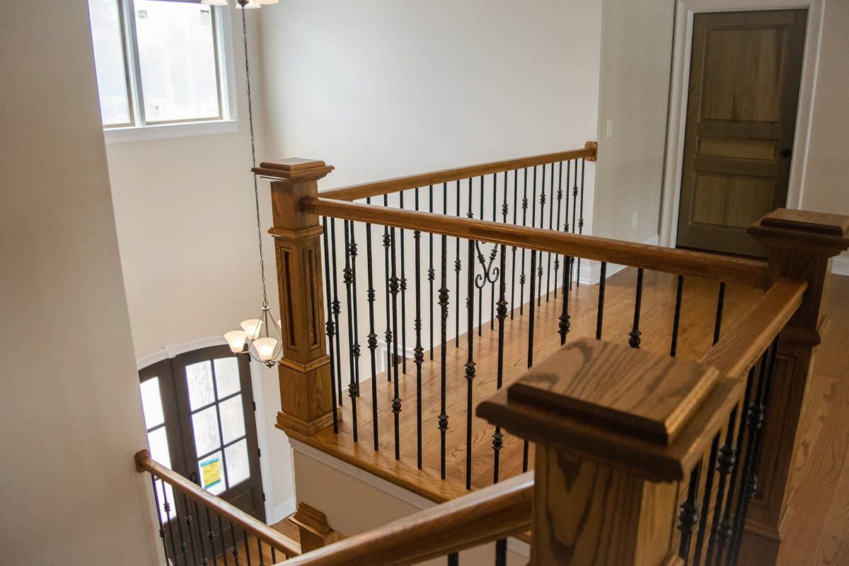Wooden staircase railing with black metal spindles.