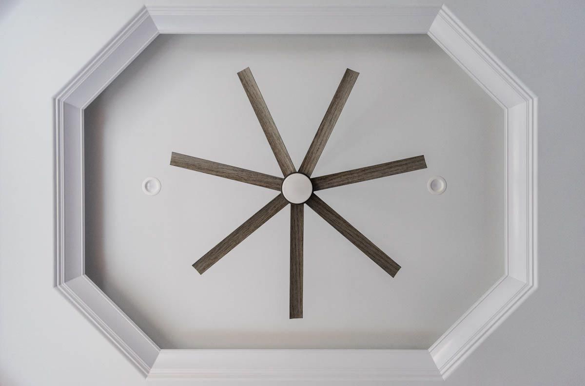 Ceiling fan with eight blades, centered in an octagonal, white ceiling.