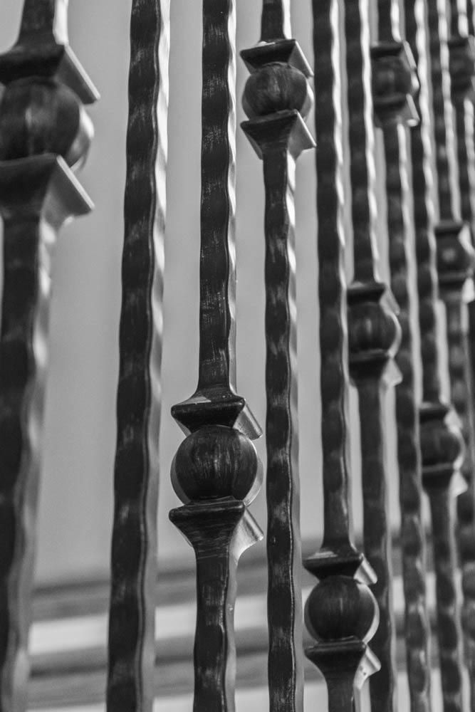 Black and white close-up of a wrought iron railing with decorative spheres.