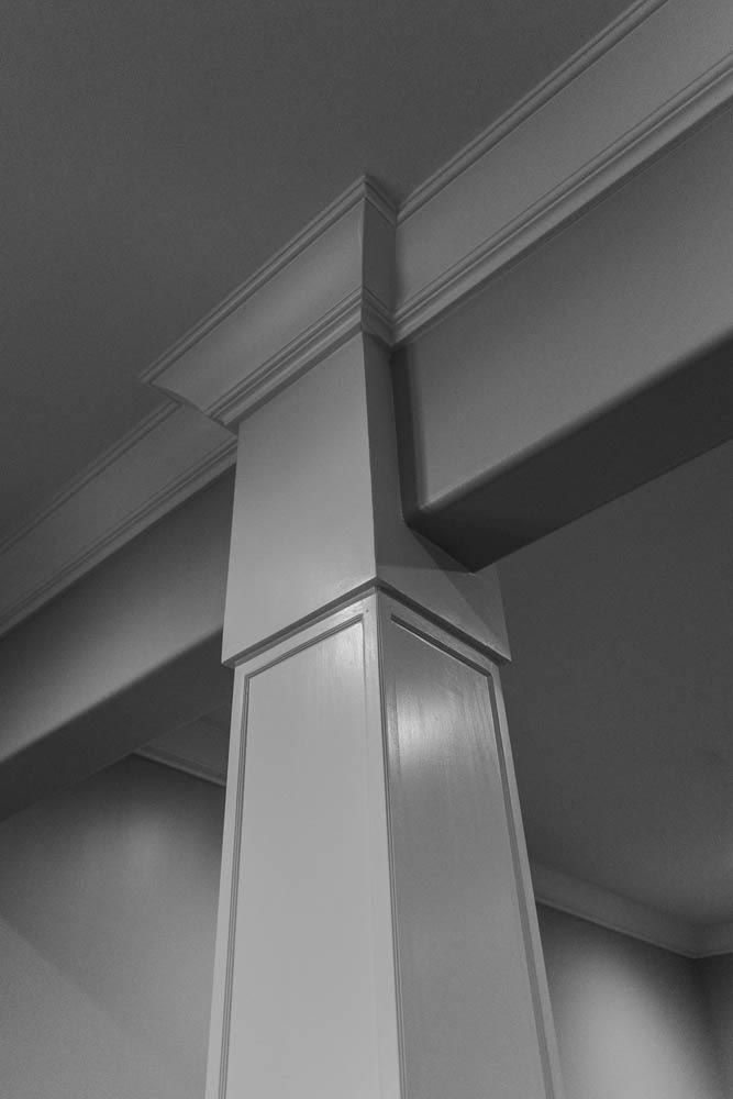 Architectural detail: white painted column supporting a ceiling beam with decorative molding.