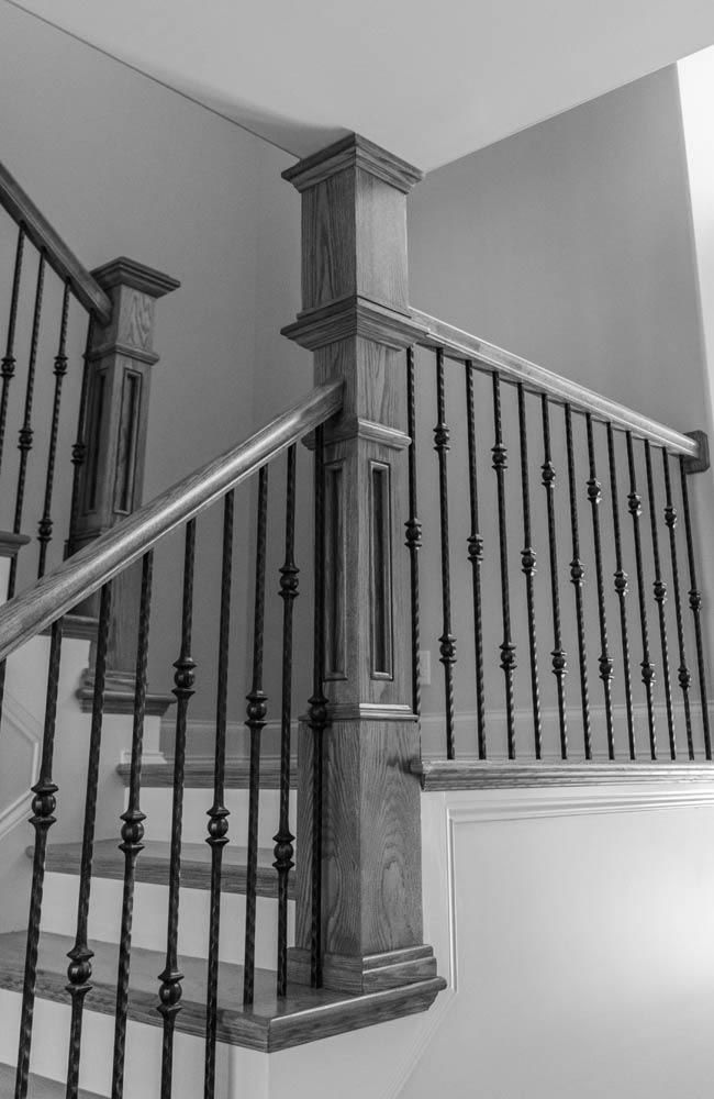 Black and white photo of a wooden staircase with iron balusters.