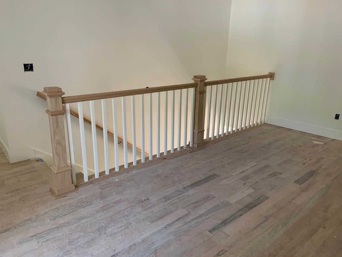 Wooden railing with white spindles and light hardwood floors.