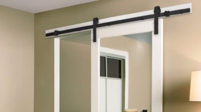 Black sliding barn door hardware on white frame, tan walls.