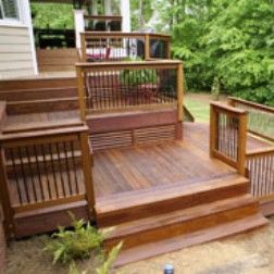 Wooden deck with steps, railings, and a small enclosure; outdoors with greenery.